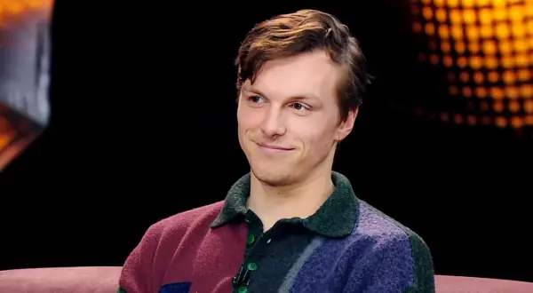 Uśmiechnięty Tomasz Włosok w kolorowym swetrze, jakby opowiadał o swoich najnowszych filmach.
