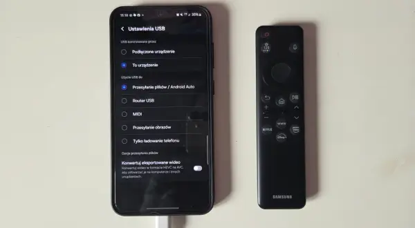 Telefon z włączonym klonowaniem ekranu obok pilota Samsunga. Ustawienia USB pokazują opcję "Przesyłanie plików / Android Auto".