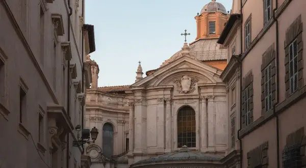 La facciata barocca della chiesa di Santa Maria della Pace si staglia tra palazzi romani, con la sua cupola imponente e le decorazioni scultoree.