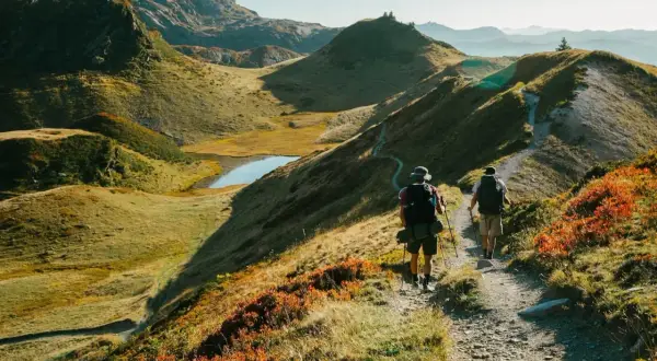 Deux randonneurs explorent un sentier de montagne pittoresque, profitant des couleurs d'automne et des paysages magnifiques. Les fiz sont en pleine aventure.