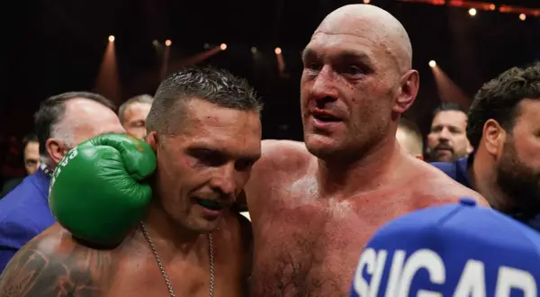 Två boxare, en med blod i ansiktet, omfamnar varandra. Tyson Fury vikt är en viktig faktor i deras matcher.