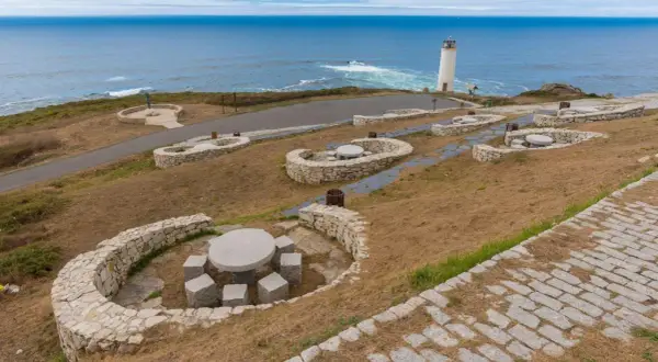 Faros de la Costa da Morte vigilando el Atlántico. Bancos de piedra y mesas invitan a contemplar el paisaje marino.