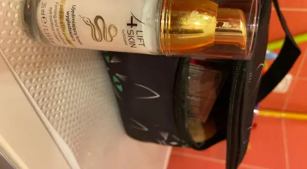 Krem pod oczy 4 Lift Skin ujędrnia i wygładza skórę. Złota pompka i czarna kosmetyczka z kocimi uszami.