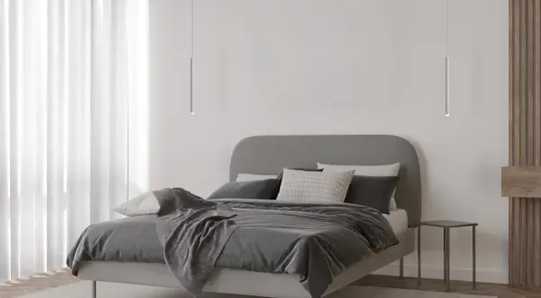 Minimalistyczna sypialnia z łóżkiem i dwoma lampami wiszącymi tuba, które dodają nowoczesnego charakteru.