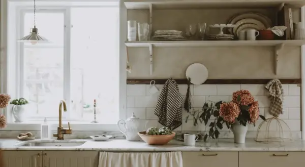 Köksbänk med diskho, kran och blommor. Skåpluckor i ljusbeige färg, redo att måla luckor för en ny stil.