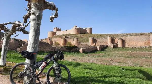 Bicicleta de montaña lista para rutas en bici por Soria, con un castillo medieval al fondo.