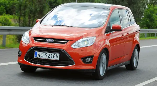 Pomarańczowy Ford C-Max na drodze. Wiele osób szuka ford c max opinie przed zakupem.