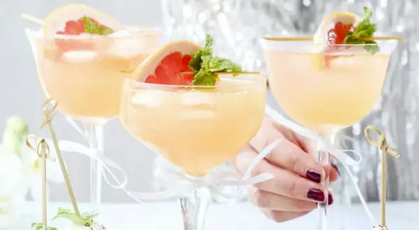 Tre eleganta glas med rosa drinkar, garnerade med grapefrukt och mynta. Perfekt drink till nyår!