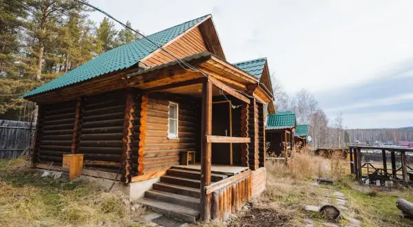 Solidny fundament pod domek letniskowy z bali, z zielonym dachem i drewnianą werandą.