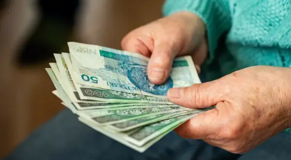 Dłonie liczą banknoty. Czy to dodatek do emerytury za warunki szkodliwe?
