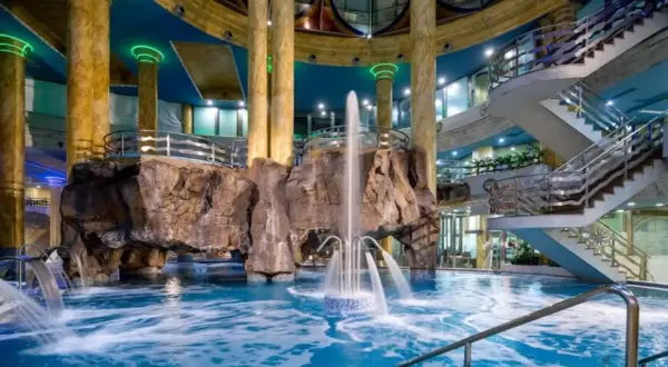Interior de un balneario en la Comunidad Valenciana con piscina, cascadas, rocas artificiales y escaleras.