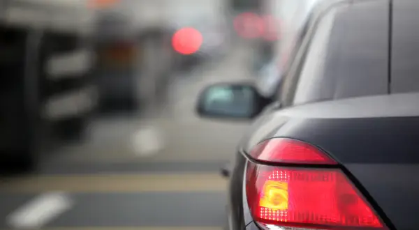 Gros plan sur les feux arrière d'une voiture dans un trafic dense. Le feu de freinage est allumé, signalant un arrêt imminent.