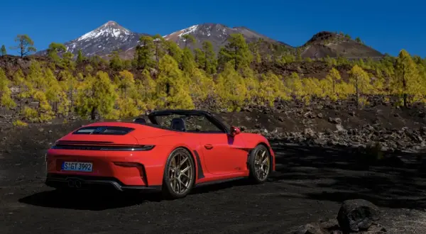 Czerwony kabriolet Porsche GT3 na tle gór i żółtych drzew. Czy to najładniejsze auto na świecie?