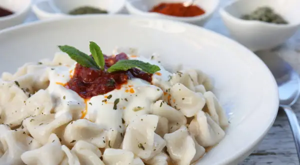 En skål med manti, små dumplings med yoghurt, tomatsås och mynta. Ett utsökt manti recept att prova!