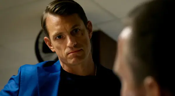Joel Kinnaman i blå kavaj, intensiv blick mot någon i närbild. Ser ut som en scen från en ny serie.