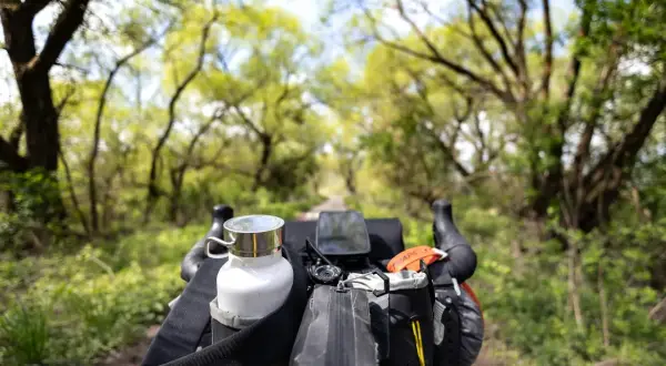 Widok z kierownicy roweru podczas bikepacking gravel. Biała butelka, nawigacja i torba podsiodłowa gotowe na przygodę.