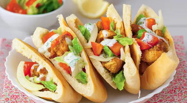 Cinco deliciosos panes de pita rellenos de pollo crujiente, lechuga, tomate y aderezo cremoso.