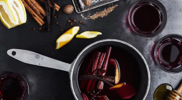 Aromatyczne wino z herbaty, z cynamonem, goździkami i skórką pomarańczy, gotowe do podania w szklankach.