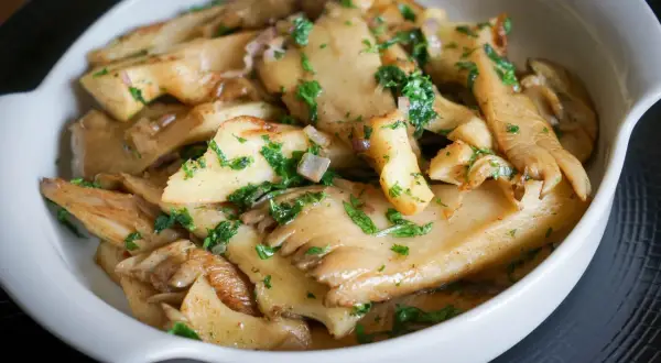 Délicieuse pleurote recette, des champignons sautés aux herbes fraîches dans un plat blanc.