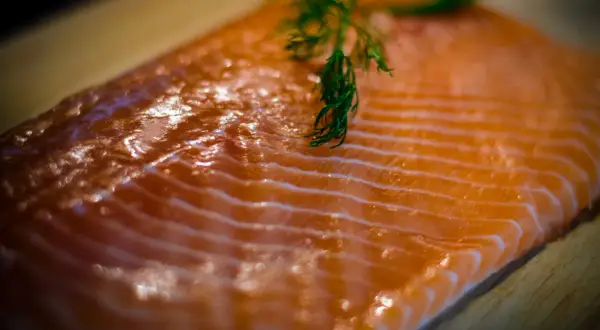 Świeży kawałek łososia z gałązką koperku. Zastanawiasz się, ile kcal ma łosoś? To zdrowe i pyszne danie.