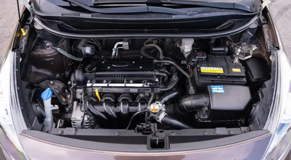 Silnik Kia Rio 3 z widocznym akumulatorem, przewodami i innymi elementami układu napędowego.