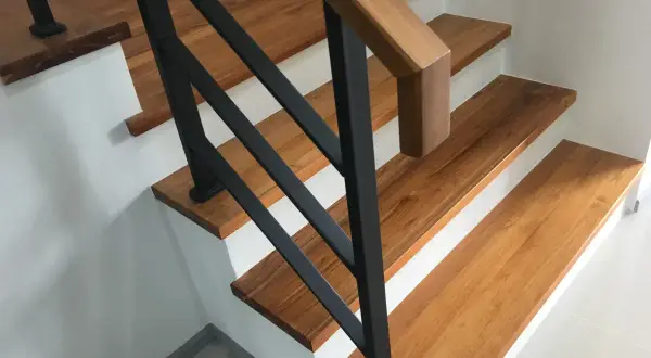 Moderne Treppen aus Holz mit schwarzem Geländer in einem Einfamilienhaus.