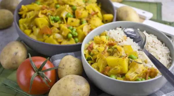 Herzhaftes Gericht mit Kartoffeln, Erbsen und Kohl, erinnert an bremer scheerkohl. Daneben Reis und frische Zutaten.
