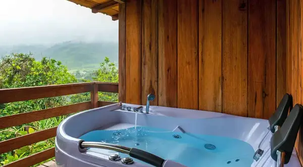 A newly completed hot tub installation on a wooden deck, overlooking a misty mountain landscape.