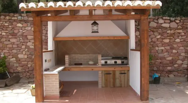 Barbacoa de obra con estructura de madera y tejado de tejas. Ideal para aprender como hacer una barbacoa de obra y disfrutar del exterior.