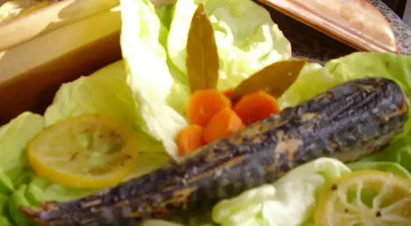 Un maquereau au vin blanc, servi sur un lit de laitue avec des carottes et des rondelles de citron.