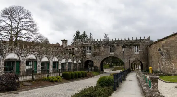 El Pazo de Coton, con su arquitectura de piedra y arcos, se alza bajo un cielo nublado, invitando a un paseo tranquilo.