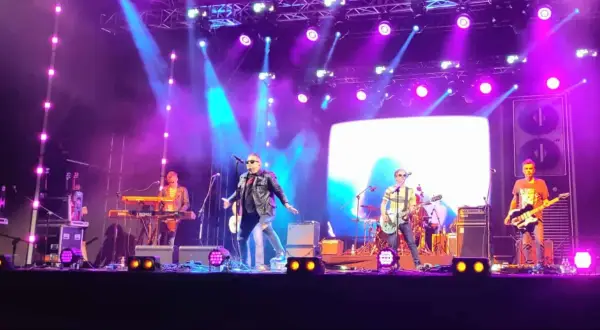 Zespół gra na scenie podczas koncertów w Stalowej Woli. Wokalista w skórzanej kurtce, gitarzyści i klawiszowiec.