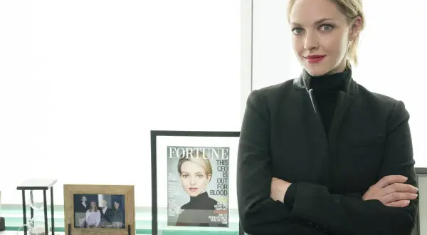Amanda Seyfried som Elizabeth Holmes i "The Dropout", med armarna i kors och en tidning med hennes ansikte på.