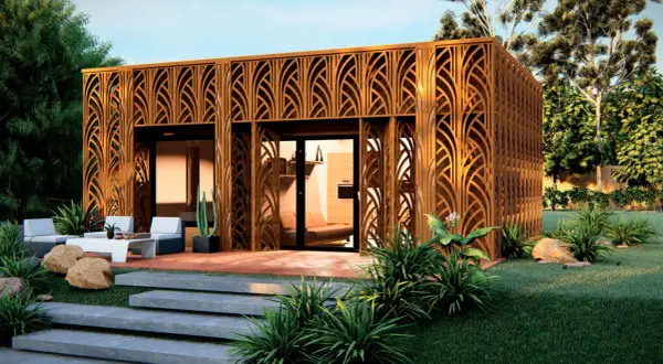 Moderna pared prefabricada exterior con diseño de celosía de madera, rodeada de vegetación y un área de descanso.