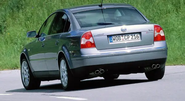 Srebrny Volkswagen Passat, wyglądający jak sleeper car, jedzie po drodze.