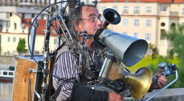 Ein Mann spielt auf einem selbstgebauten Blechblas-Instrument, das mit einem Banjo und vielen mechanischen Teilen verbunden ist.