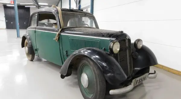 En grön och svart DKW med en spånkorgsdetalj på taket, står i ett garage.