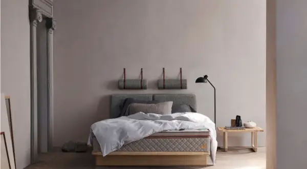 Stilvolles Schlafzimmer mit grauem Bett, minimalistischer Deko und warmem Holzboden. Tolle Schlafzimmer Ideen für Ruhe.