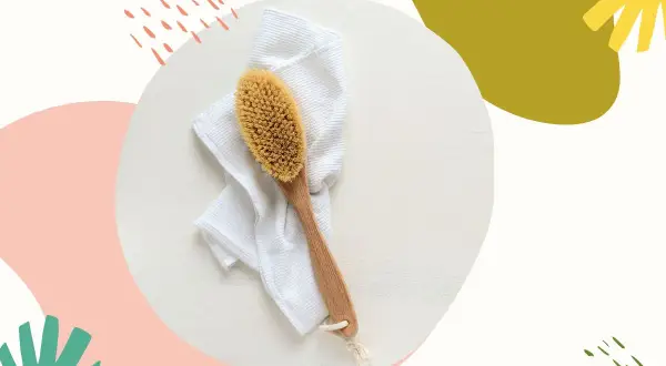 Szczotka do szczotkowania twarzy leży na białym ręczniku. Idealny zestaw do domowego SPA.