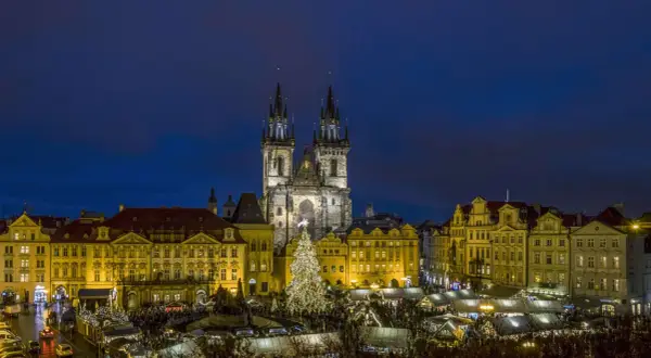 Prag im Winter: Der beleuchtete Weihnachtsbaum auf dem Altstädter Ring, umgeben von Ständen und der Teynkirche, erstrahlt in der Dämmerung.