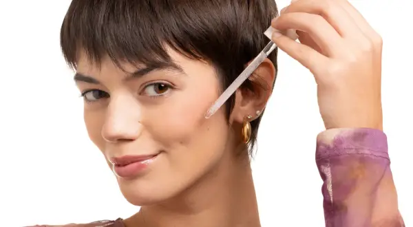 Una donna applica un siero viso con contagocce. Scopri a cosa serve la vitamina C per il viso per una pelle luminosa.