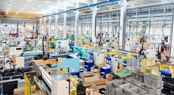 Nowoczesna hala produkcyjna z liniami maszyn, robotami i taśmociągami. Efektywne zarządzanie produkcją w akcji.