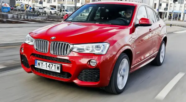 Czerwone BMW X4 w ruchu miejskim. Wady tego modelu to m.in. ograniczona widoczność z tyłu i wysoka cena.