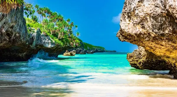 Rajska plaża na Zanzibarze, z turkusową wodą i skalistymi klifami porośniętymi zielenią. Idealne miejsce, by zobaczyć, co Zanzibar ma do zaoferowania.