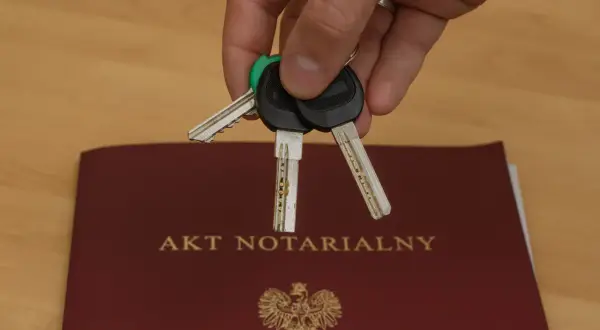 Klucze do nowego domu leżą na akcie notarialnym, symbolizującym własność.