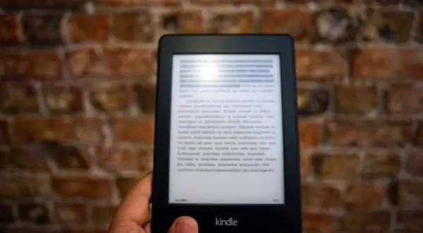 Dłoń trzyma czytnik Kindle z tekstem. Komputer nie widzi Kindla, mimo że jest podłączony.