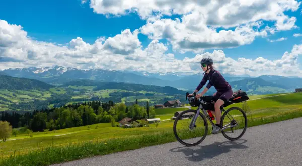 Frau auf Radtour durch Deutschland, genießt die Aussicht auf grüne Hügel und Berge. Perfekt für eine 3 Tage Radtour Deutschland.