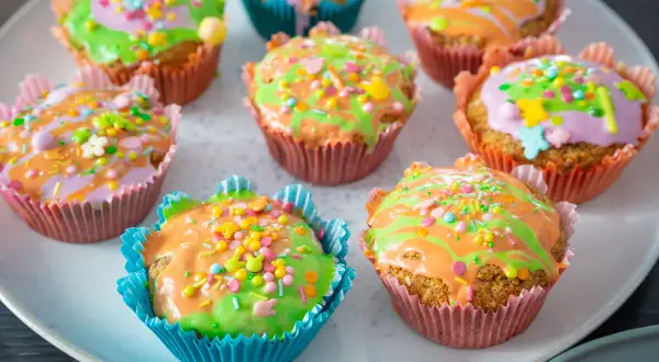 Bunte Karotten Muffins mit Zuckerguss und Streuseln, perfekt für Ostern.