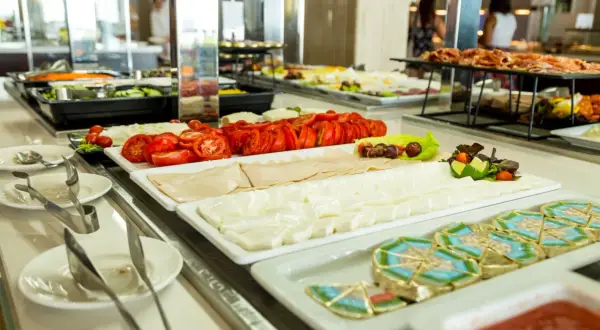 Una variada selección de quesos, fiambres y tomates frescos en una barra de buffet, como en una taberna oasis.