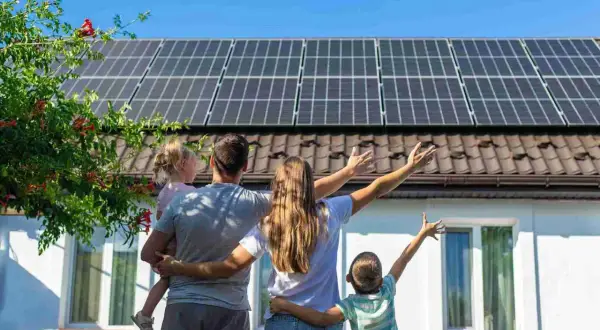 Familia celebra el **revamping fotovoltaico** de su hogar, con paneles solares en el tejado y un futuro brillante.